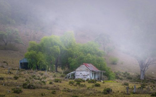 Old white house in the hillside with rainy mist rolling down
